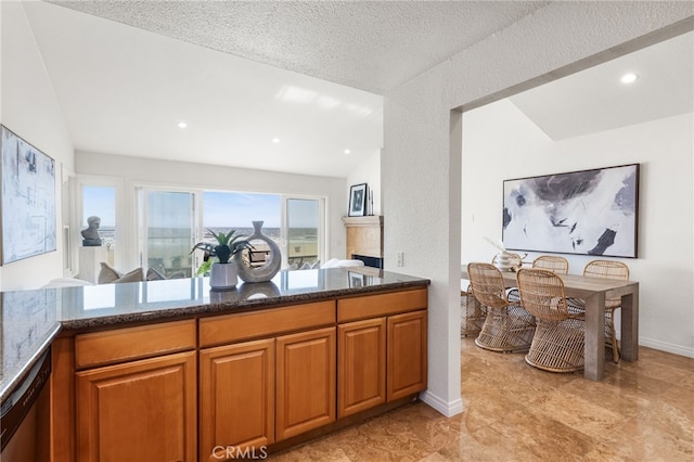 3012 W Oceanfront, Newport Beach, CA 92663 - kitchen featuring dark stone countertops, brown cabinets, stainless steel dishwasher, a textured ceiling, and vaulted ceiling