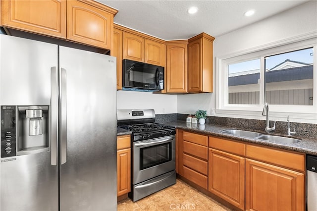 3012 W Oceanfront, Newport Beach, CA 92663 - kitchen with stainless steel appliances, a sink, brown cabinets, dark stone counters, and recessed lighting