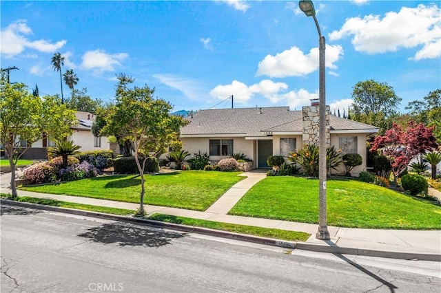 ranch-style home with stucco siding and a front lawn