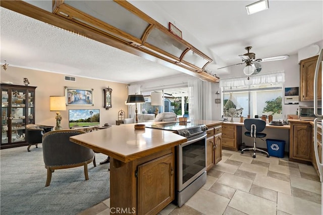 kitchen with visible vents, a center island, light countertops, stainless steel electric stove, and a ceiling fan