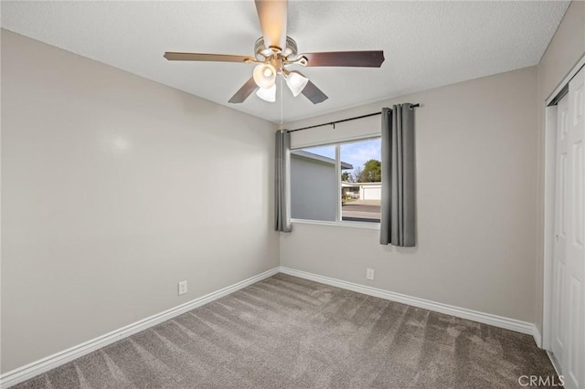 carpeted spare room with baseboards, a textured ceiling, and ceiling fan