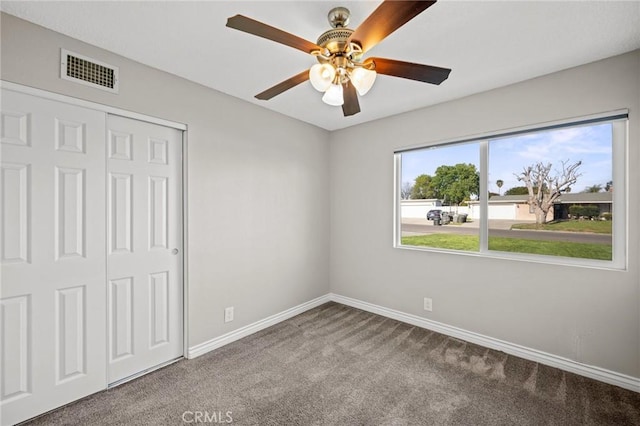 unfurnished bedroom with a closet, baseboards, carpet flooring, visible vents, and ceiling fan