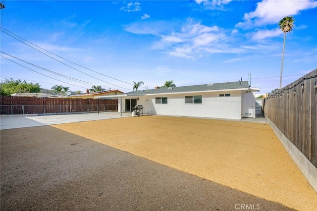 back of property with a patio area, stucco siding, and a fenced backyard