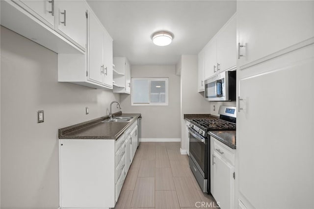 kitchen with stainless steel appliances, white cabinetry, a sink, and dark countertops