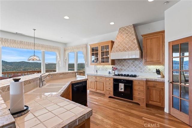 29083 Mammoth Dr, Lake Arrowhead, CA 92352 - kitchen with black appliances, custom range hood, light wood-type flooring, backsplash, and pendant lighting