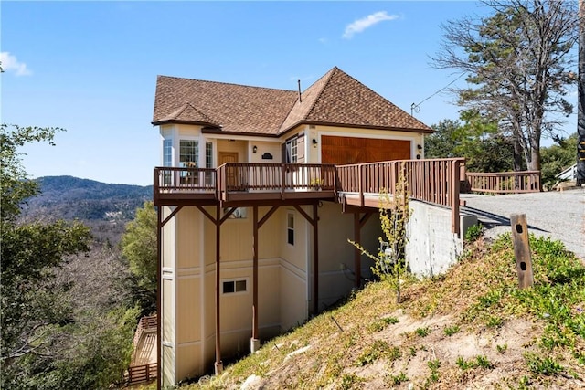 29083 Mammoth Dr, Lake Arrowhead, CA 92352 - rear view of house featuring a deck with mountain view, a shingled roof, gravel driveway, and an attached garage