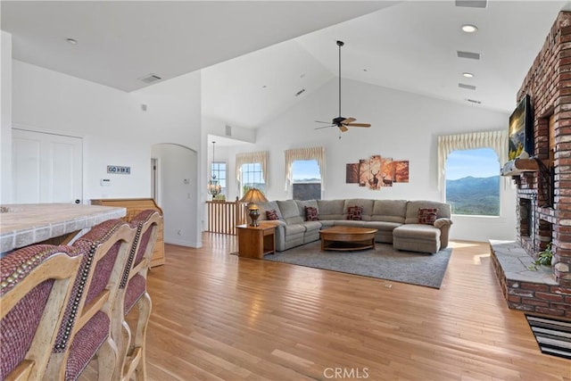29083 Mammoth Dr, Lake Arrowhead, CA 92352 - living area with a brick fireplace, light wood-style flooring, arched walkways, a ceiling fan, and plenty of natural light