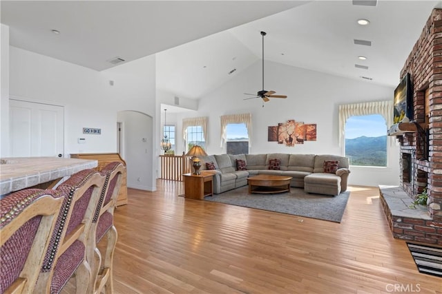 29083 Mammoth Dr, Lake Arrowhead, CA 92352 - living room with a brick fireplace, light wood-style floors, ceiling fan, arched walkways, and healthy amount of natural light