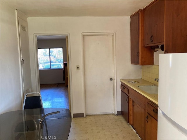 kitchen featuring light countertops, brown cabinets, freestanding refrigerator, and light floors