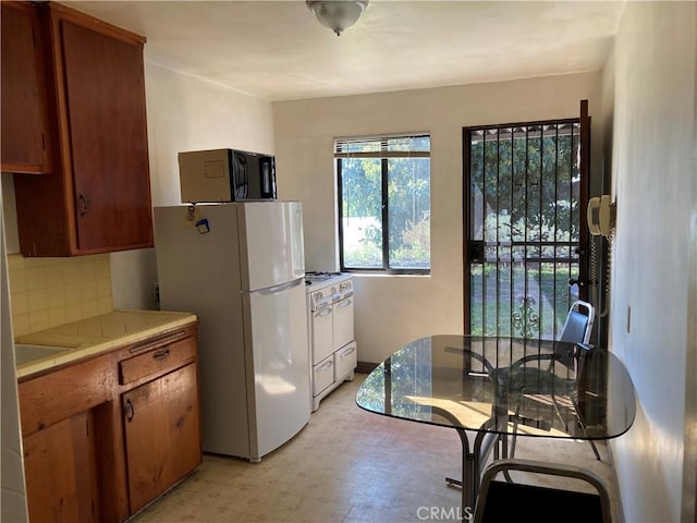 kitchen with brown cabinets, white appliances, tile countertops, and light floors