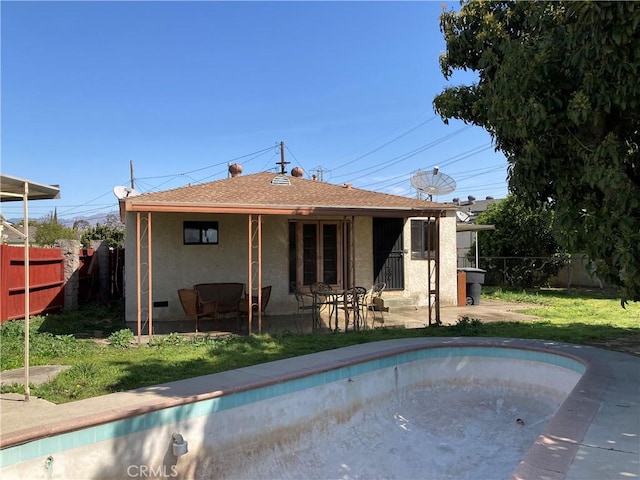 back of house featuring stucco siding, a lawn, a patio, roof with shingles, and fence