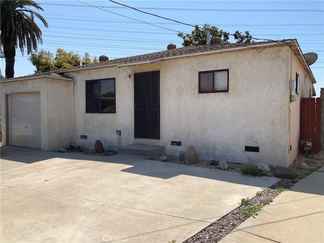 view of front of property with an attached garage, fence, crawl space, and stucco siding