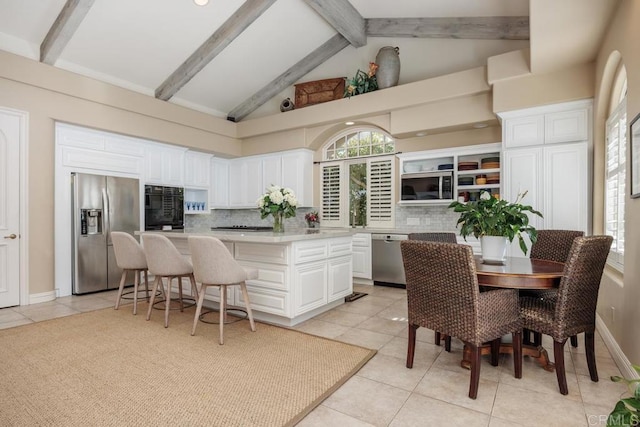7189 Aviara Dr, Carlsbad, CA 92011 - kitchen with appliances with stainless steel finishes, light tile patterned flooring, a kitchen island, decorative backsplash, and white cabinetry