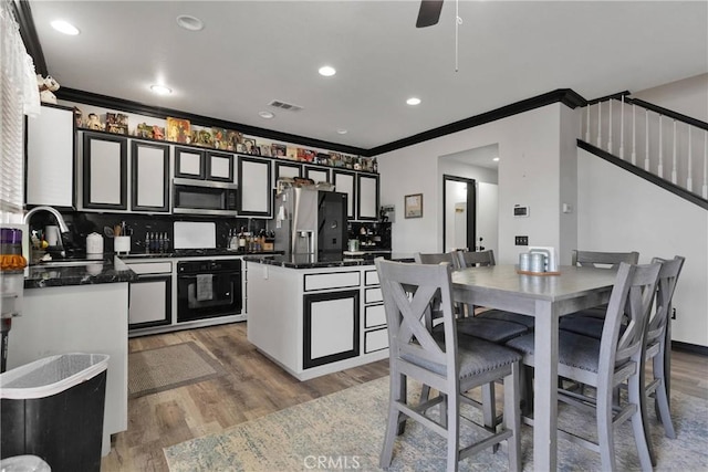 9153 Ravenswood Ave, Hesperia, CA 92344 - kitchen with crown molding, dark countertops, visible vents, appliances with stainless steel finishes, and a sink