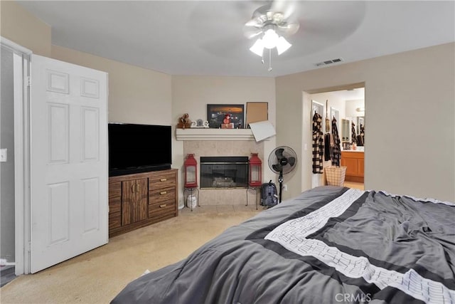 9153 Ravenswood Ave, Hesperia, CA 92344 - carpeted bedroom with a tiled fireplace, visible vents, connected bathroom, and ceiling fan