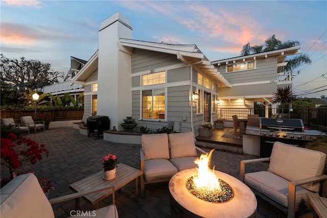 361 Cress St, Laguna Beach, CA 92651 - back of property at dusk with an outdoor living space with a fire pit, a patio, a chimney, and fence
