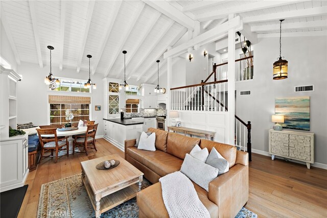 361 Cress St, Laguna Beach, CA 92651 - living room featuring stairs, light wood-style floors, a chandelier, beamed ceiling, and high vaulted ceiling