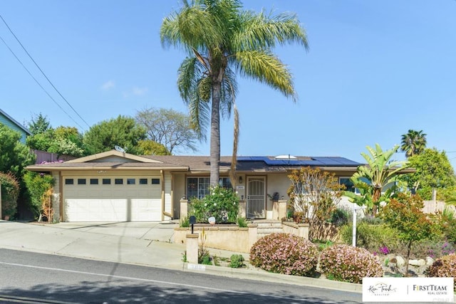 single story home featuring a garage, stucco siding, roof mounted solar panels, and concrete driveway