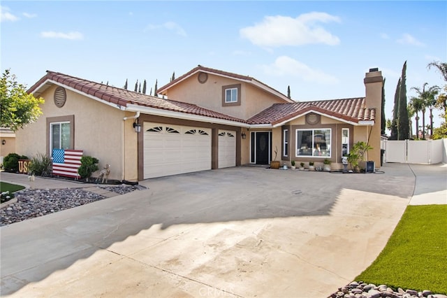 view of front of house with driveway, a tiled roof, an attached garage, fence, and stucco siding