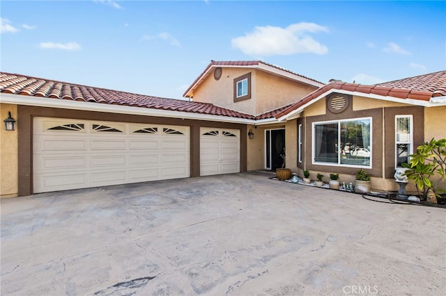 mediterranean / spanish-style house featuring an attached garage, a tiled roof, driveway, and stucco siding