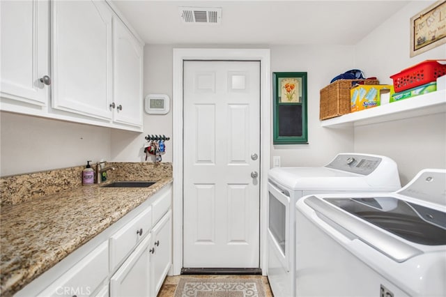 clothes washing area featuring washing machine and clothes dryer, visible vents, a sink, and cabinet space