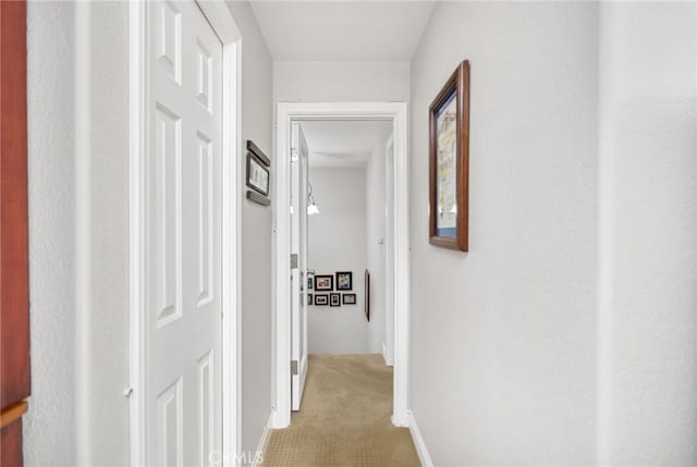 corridor featuring light carpet and baseboards