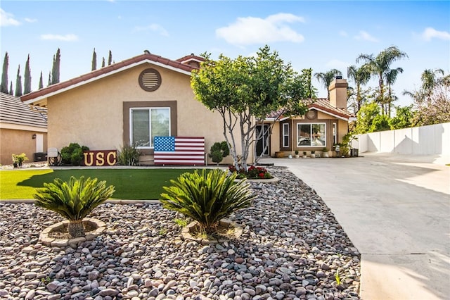 mediterranean / spanish-style house with fence, a tiled roof, concrete driveway, stucco siding, and a front yard
