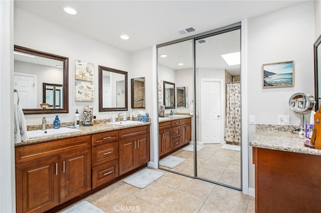 full bath with a skylight, visible vents, a sink, and double vanity