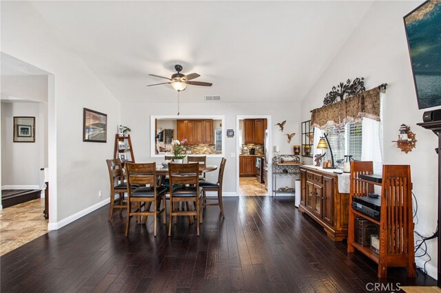 dining room with a ceiling fan, baseboards, wood-type flooring, lofted ceiling, and visible vents
