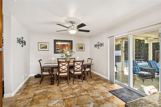 dining room featuring baseboards, a ceiling fan, and stone finish floor