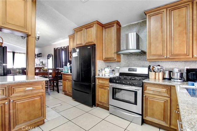 kitchen featuring wall chimney range hood, light tile patterned floors, brown cabinetry, and black appliances