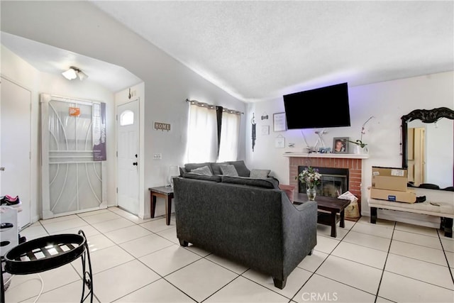 living room featuring light tile patterned floors, vaulted ceiling, a brick fireplace, and a textured ceiling