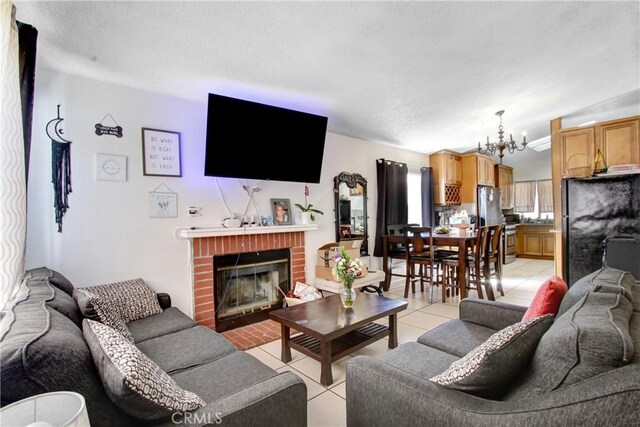 living room featuring a chandelier, a textured ceiling, light tile patterned flooring, and a fireplace