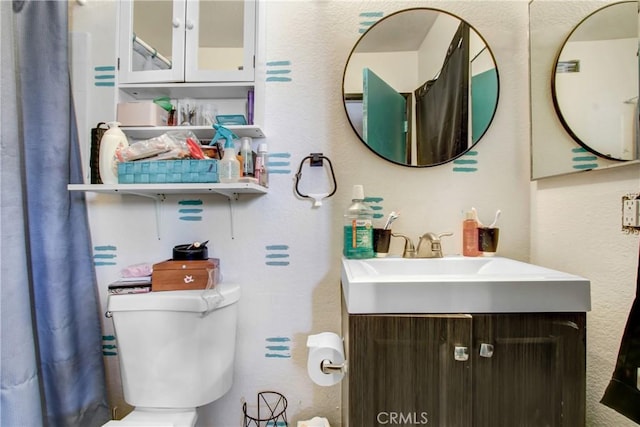 bathroom featuring a textured wall, vanity, and toilet