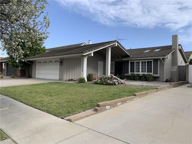 single story home featuring an attached garage, a tile roof, board and batten siding, a front yard, and concrete driveway