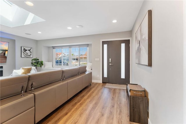 living area featuring baseboards, recessed lighting, light wood-style flooring, and a skylight