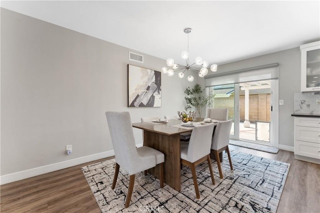 dining space with a chandelier, baseboards, visible vents, and wood finished floors