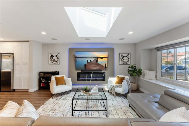 living room featuring baseboards, recessed lighting, wood finished floors, and a skylight