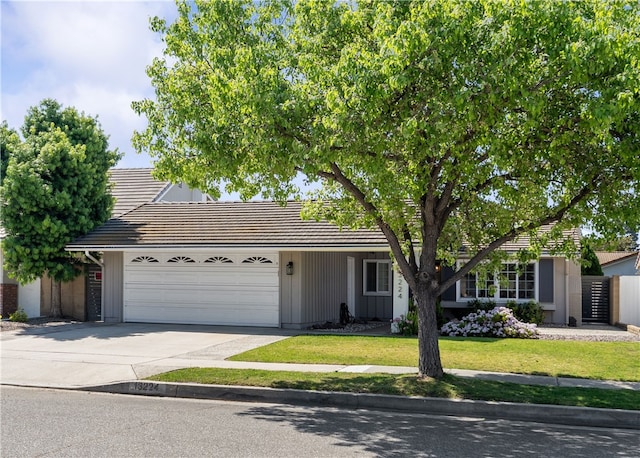 view of front of house with concrete driveway, a tile roof, a front yard, and a garage