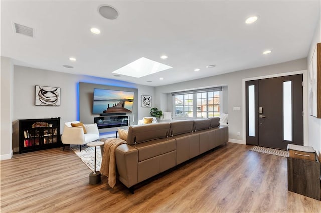 living room with visible vents, a skylight, light wood-type flooring, baseboards, and recessed lighting