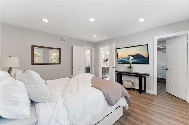 bedroom with visible vents, recessed lighting, light wood-style flooring, and a walk in closet