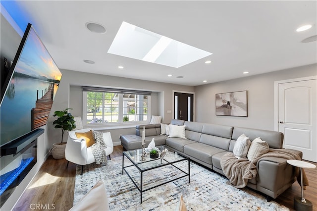 living room with baseboards, recessed lighting, a skylight, and wood finished floors