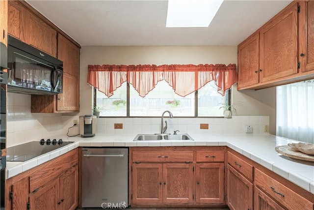 kitchen featuring a sink, a wealth of natural light, black appliances, and brown cabinets