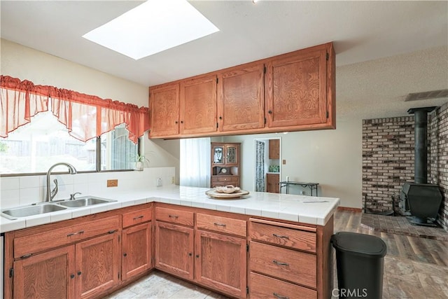 kitchen featuring a wood stove, a peninsula, brown cabinets, and a sink