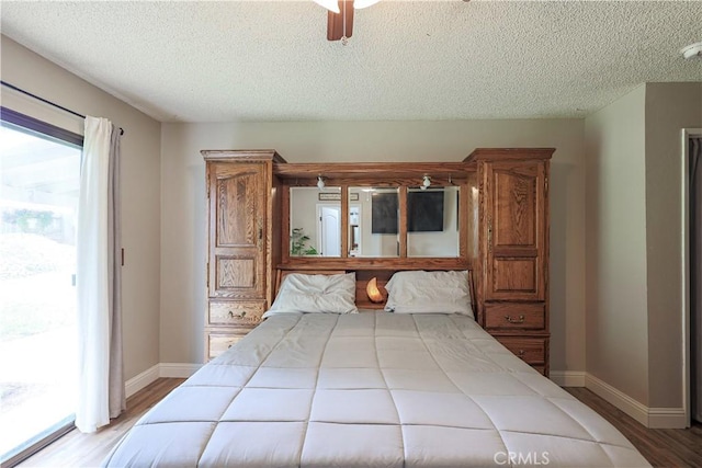 bedroom featuring baseboards, a ceiling fan, a textured ceiling, wood finished floors, and access to outside