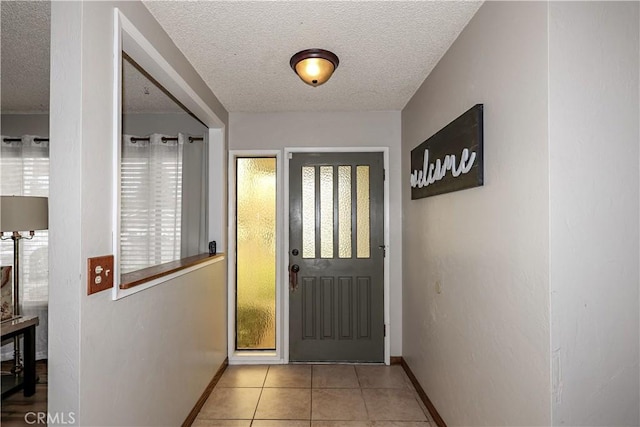 entryway featuring a textured ceiling, light tile patterned floors, and baseboards