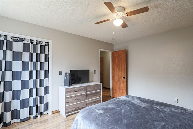 bedroom with ceiling fan, wood finished floors, and a textured ceiling