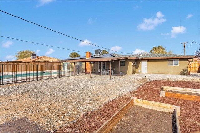 13206 Winona Rd, Apple Valley, CA 92308 - rear view of property with a fenced in pool, a patio, solar panels, a fenced backyard, and a vegetable garden