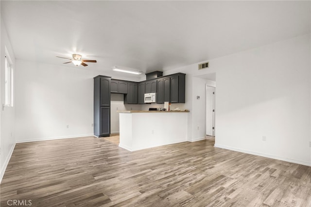 unfurnished living room with visible vents, light wood-type flooring, and a ceiling fan