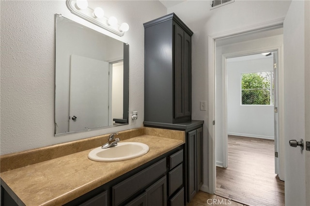 bathroom featuring visible vents, baseboards, vanity, and wood finished floors